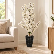Arbre artificiel à fleurs blanches avec pot noir dans un coin de salon – Plantora